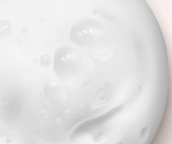 Close-up of white cream or lotion with a light pink background