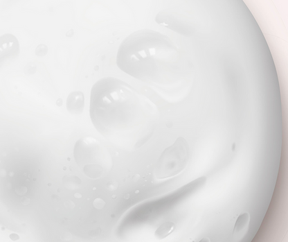 Close-up of white cream or lotion with a light pink background